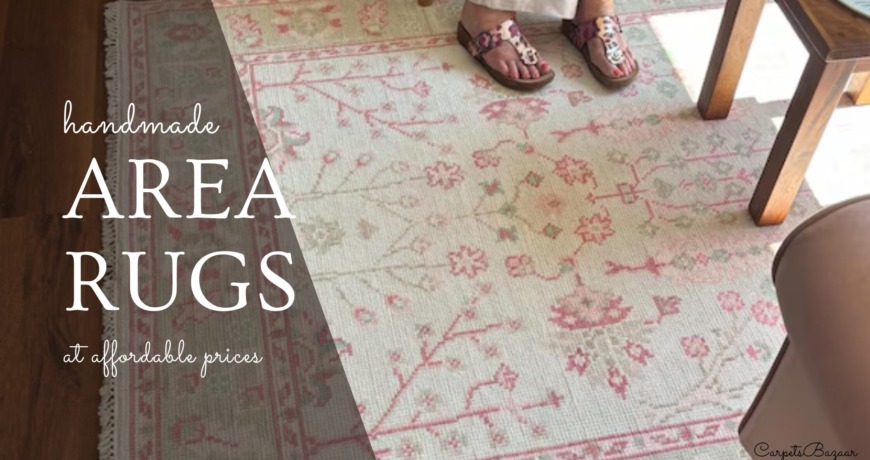 handmade area rug in ivory light green and pink laid under a wood coffee table and next to a sofa.