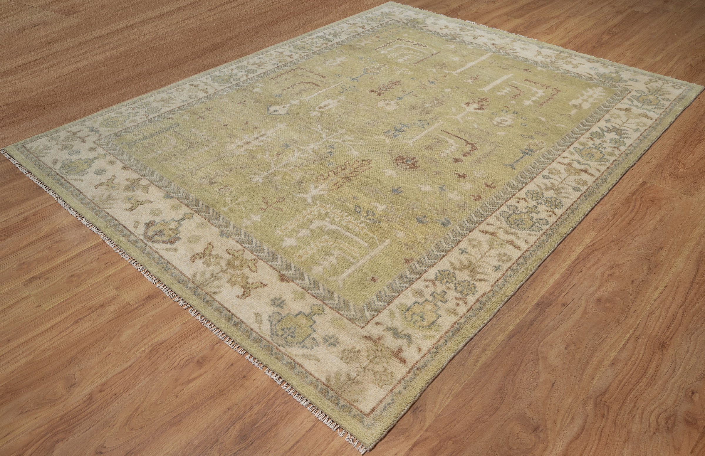 Hand-knotted wool Oushak rug with a sage-green field, ivory multi-band border, and scattered botanical palmette and tree motifs in soft rust, cream, and slate tones.