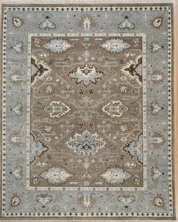 Hand-knotted wool Oushak rug with a taupe field, wide grey border, and tonal palmette, vine, and serrated-leaf motifs in ivory, brown, and charcoal.