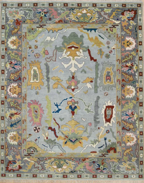 Hand-knotted wool Oushak rug with a grey field, wide charcoal border, and oversized palmette, rosette, vine, and serrated-leaf motifs in gold, burgundy, olive, blush, and navy.