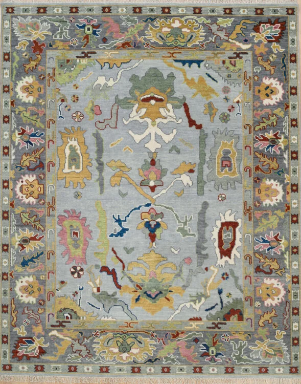 Hand-knotted wool Oushak rug with a grey field, wide charcoal border, and oversized palmette, rosette, vine, and serrated-leaf motifs in gold, burgundy, olive, blush, and navy.