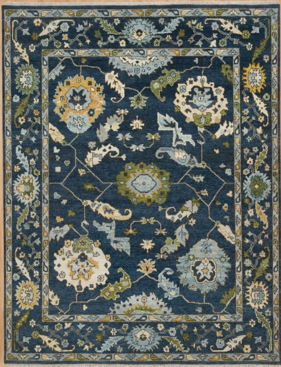 Hand-knotted wool Oushak rug with a deep navy field, wide navy border, and oversized palmette, rosette, vine, and serrated-leaf motifs in olive, gold, ivory, and teal.