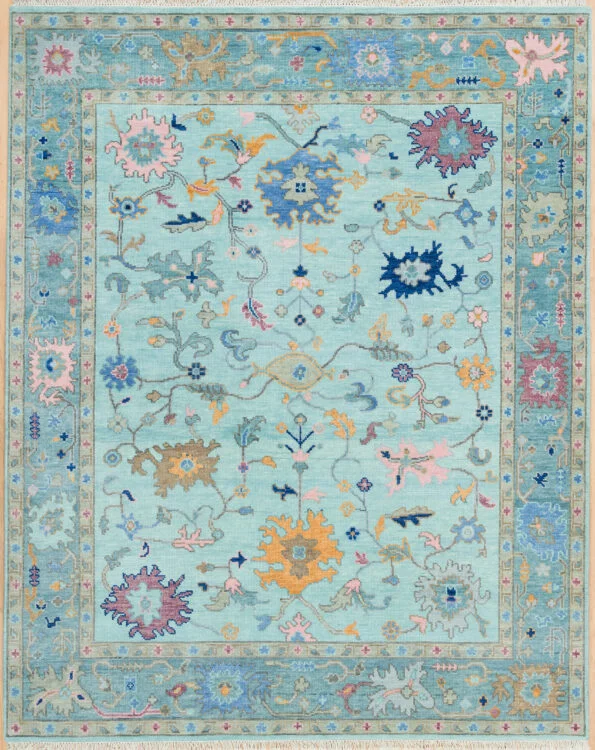 Hand-knotted wool oushak rug with a light aqua field, wide teal border, and scattered palmette, rosette, and vine motifs in blue, gold, and blush with generous spacing.