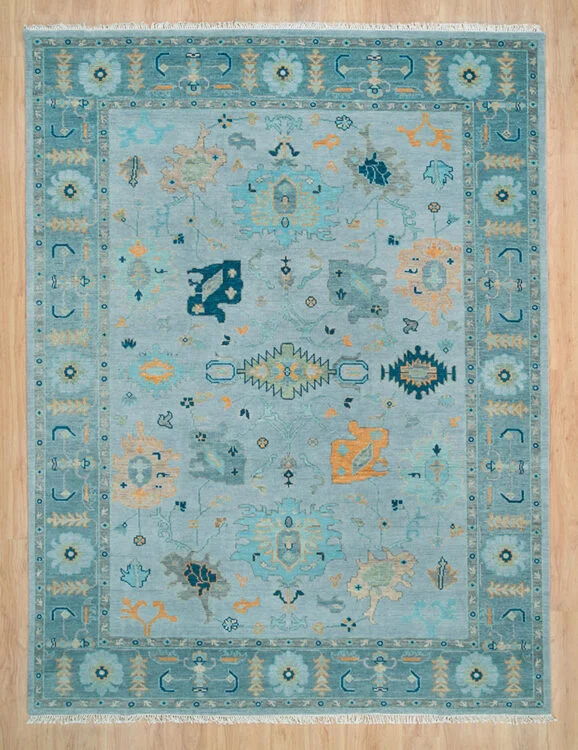 Hand-knotted wool oushak rug with a soft aqua field, wide teal border, and tonal palmette, vine, serrated-leaf, and cypress motifs in teal and gold with subtle figure-ground contrast.