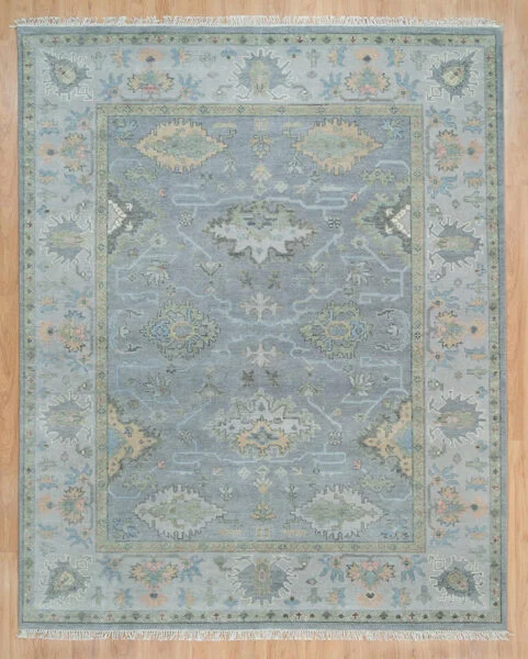 Hand-knotted wool oushak rug with a pale grey field, wide grey-sage border, and softly tonal palmettes, rosettes, and vine motifs in sage, blue, gold, and blush.