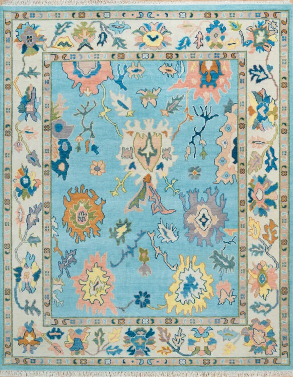 Hand-knotted wool oushak rug with a light aqua field, wide ivory border, and scattered palmettes and rosettes in blush, gold, navy, and sage with lively but balanced spacing.