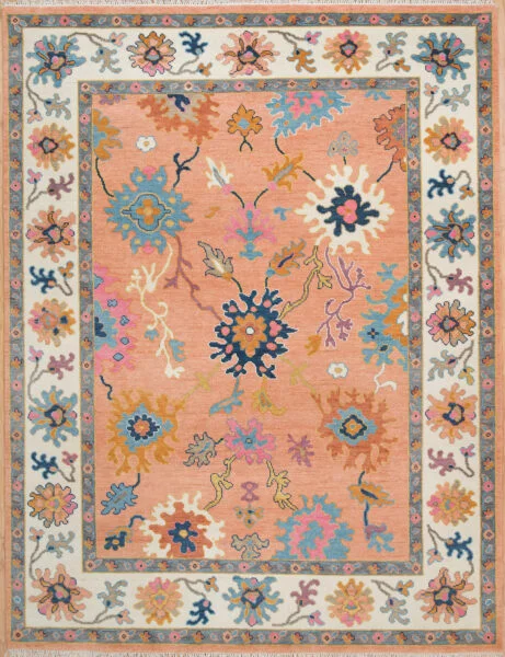 Hand-knotted wool oushak rug with a peach field, multi-band ivory and blue border, and densely packed oversized rosettes, palmettes, and carnations in navy, blue, rose, and gold.