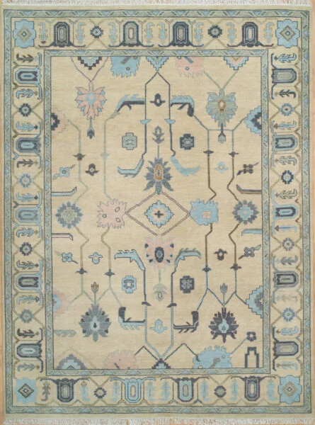 Hand-knotted wool oushak rug with a warm sand field, wide teal-grey border, and geometric palmette, angular-vine, diamond, and tulip motifs in muted navy and blue with structured, traditional character.