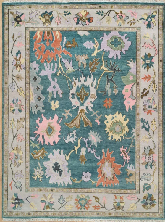 Hand-knotted wool oushak rug with a rich teal field, wide ivory border, and oversized palmettes and rosettes in vivid blush, coral, mauve, and ivory with high-drama contrast.