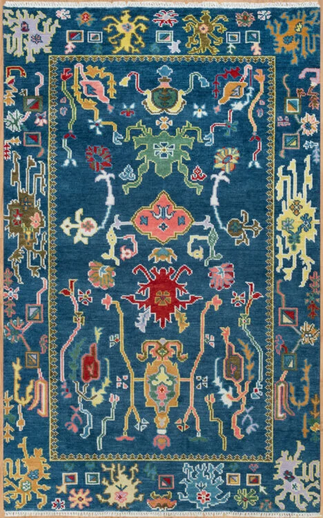 Hand-knotted wool oushak rug with a deep navy field, narrow gold-line border, and densely packed vivid palmettes, rosettes, scrolls, and a central medallion in green, red, gold, and coral.