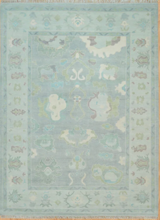 Hand-knotted wool oushak rug with a soft teal field, wide teal border, and tonal oversized palmettes, rosettes, and cloud-band motifs in sage and ivory.