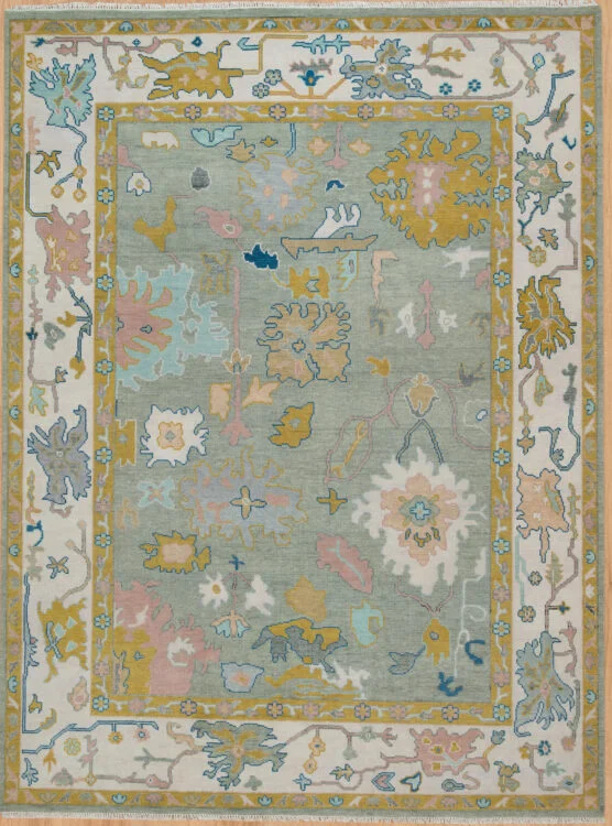 Hand-knotted wool oushak rug with a soft sage field, multi-band ivory border, and dense oversized palmettes, rosettes, and cloud-band motifs in gold, blue, blush, and ivory.