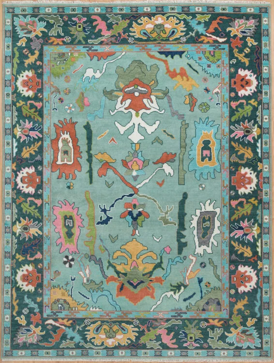 Hand-knotted wool oushak rug with a rich teal field, wide dark charcoal border, and dense oversized vivid palmettes, rosettes, and scrolls in coral, ivory, green, and rose.