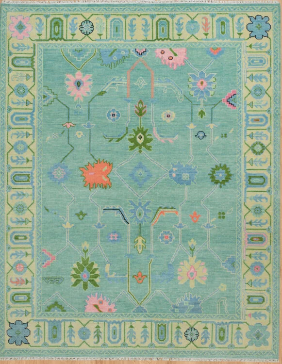 Hand-knotted wool oushak rug with a fresh green field, wide green border, and balanced palmettes, rosettes, and tulips in blue, blush, olive, and coral with moderate spacing.