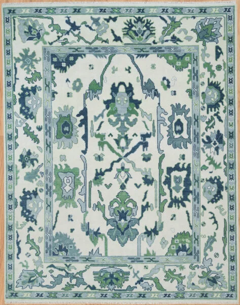Hand-knotted wool oushak rug with a bright ivory field, wide green border, and dense oversized bold palmettes and rosettes in green, navy, and teal with minimal open ground.