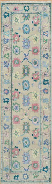 Hand-knotted wool Oushak runner with a beige field featuring palmettes and rosettes in coral, blue, green, and mauve, framed by a narrow teal border.