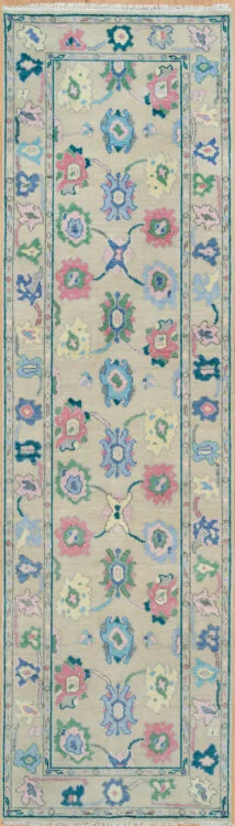 Hand-knotted wool Oushak runner with a beige field featuring palmettes and rosettes in coral, blue, green, and mauve, framed by a narrow teal border.