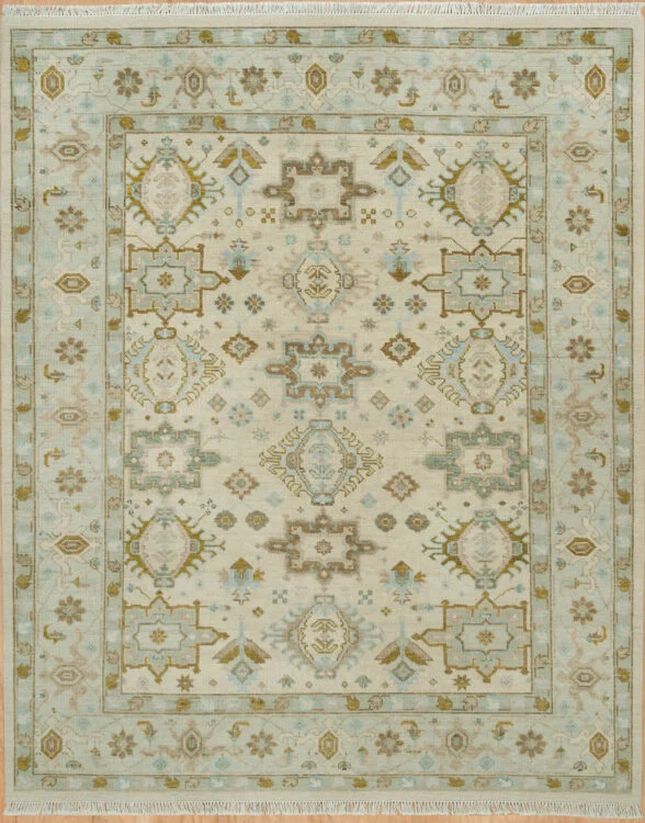 Hand-knotted wool Oushak rug with a beige field featuring palmettes and rosettes in olive and muted blue, framed by a wide pale blue border with geometric accents.