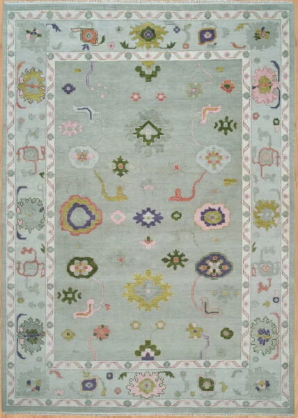 Hand-knotted wool Oushak rug with pale sage field and scattered small rosettes in green, pink, gold, and navy tones.