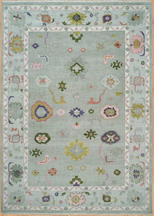 Hand-knotted wool Oushak rug with pale sage field and scattered small rosettes in green, pink, gold, and navy tones.