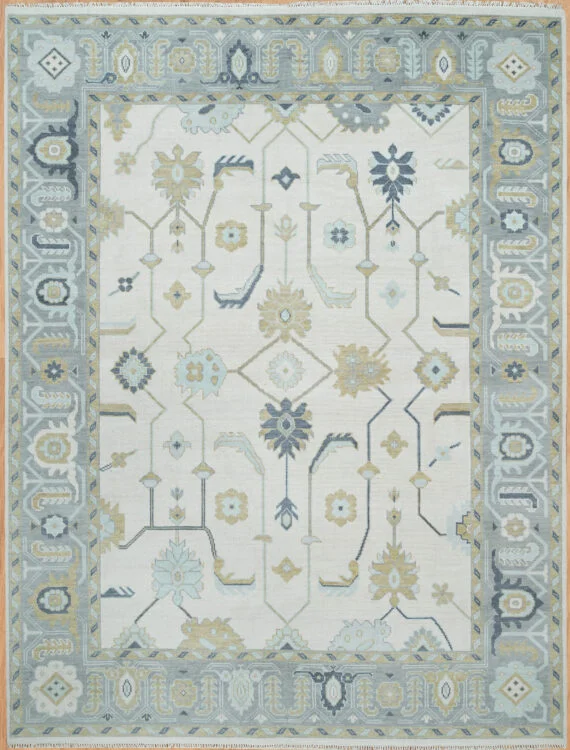 Hand-knotted wool Oushak rug with ivory field, blue-grey border, and all-over floral palmettes in blue and gold.