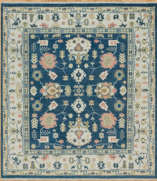 Hand-knotted wool Oushak rug with deep navy field, ivory border, and floral palmettes in ivory, peach, gold, and green.