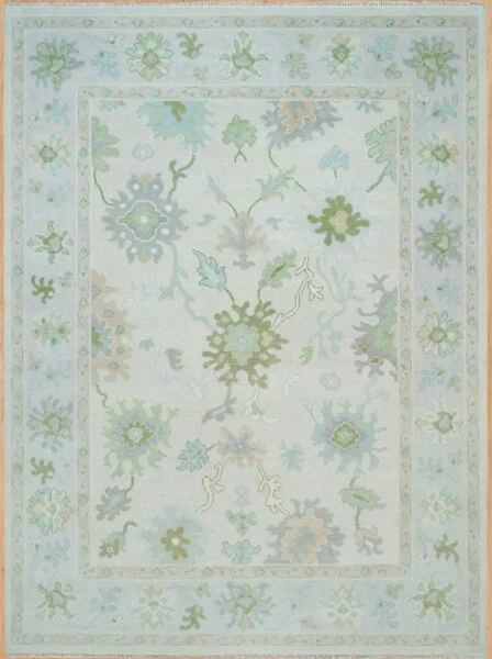 Hand-knotted wool Oushak rug with very light ivory field and pastel floral palmettes in sage, blue, and green.