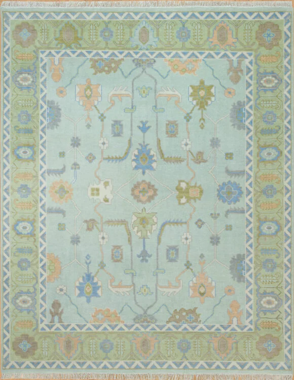 Hand-knotted wool Oushak rug with sage field, green and blue border, and floral palmettes in blue, peach, gold, and green.