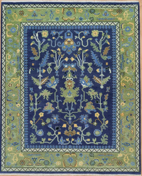 Hand-knotted modern Oushak wool rug with a deep navy field, large green palmettes and gold floral motifs, and a wide green scrolling vine border.
