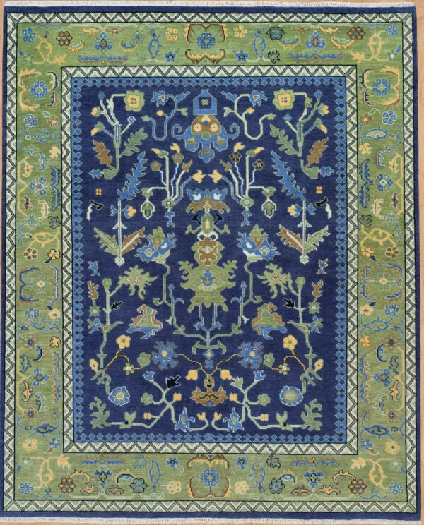 Hand-knotted modern Oushak wool rug with a deep navy field, large green palmettes and gold floral motifs, and a wide green scrolling vine border.
