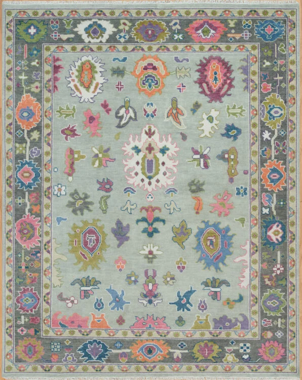 Hand-knotted modern Oushak wool rug with a sage green field covered in colourful abstract palmettes in coral, pink, navy and olive, with a grey floral border.