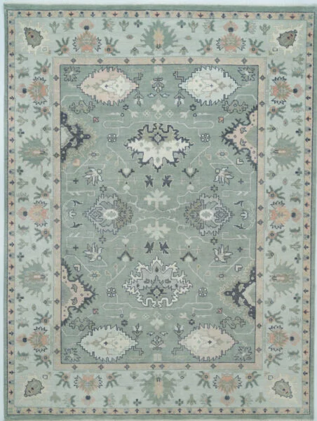 Hand-knotted modern Oushak wool rug with a muted sage green field, tonal grey and sage palmettes, small peach accents and a soft grey border.