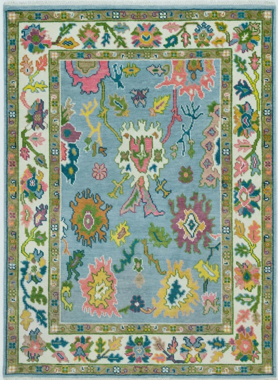 Hand-knotted modern Oushak wool rug with a powder-blue field and oversized coral, pink, yellow and green florals, with an ivory floral border.
