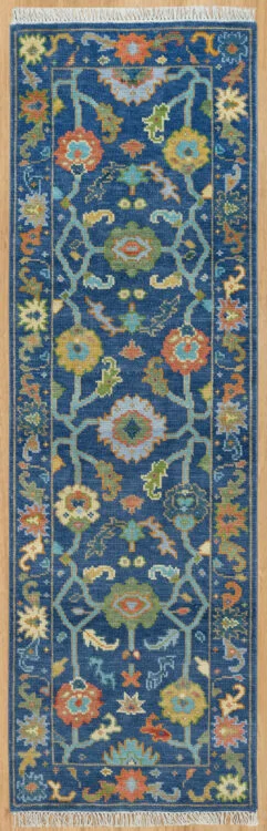 Hand-knotted modern Oushak wool runner with a deep navy field, densely packed blue, green and coral floral motifs, and a subtle tonal border.