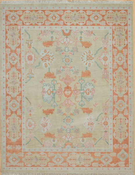 Hand-knotted modern Oushak wool rug with a warm beige field, soft coral and teal palmettes, and a wide coral border with scrolling floral motifs.
