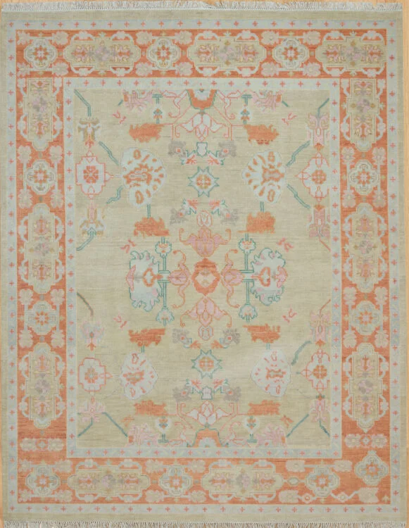 Hand-knotted modern Oushak wool rug with a warm beige field, soft coral and teal palmettes, and a wide coral border with scrolling floral motifs.