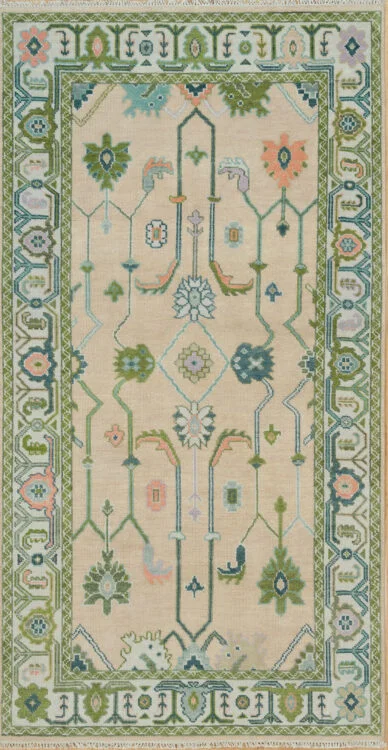 Hand-knotted modern Oushak wool rug with a warm beige field, green and sage palmettes with coral accents, and a wide sage geometric-floral border.