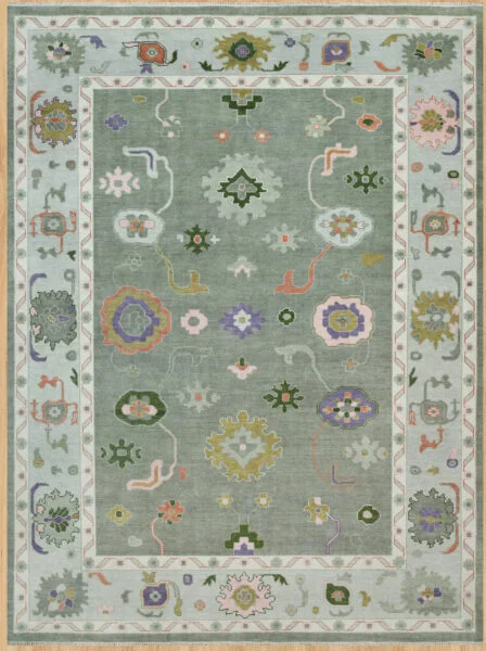 Hand-knotted modern Oushak wool rug with a muted sage field, green, ivory and coral florals, and a wide pale sage border with complementary rosettes.