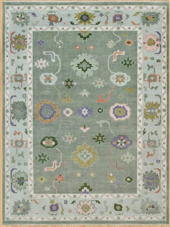 Hand-knotted modern Oushak wool rug with a muted sage field, green, ivory and coral florals, and a wide pale sage border with complementary rosettes.