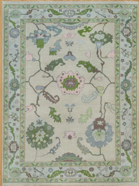 Hand-knotted wool oushak rug with a pale sage field, wide green border, and open large-scale palmettes, rosettes, and cloud-bands in green, blush, blue, and brown.