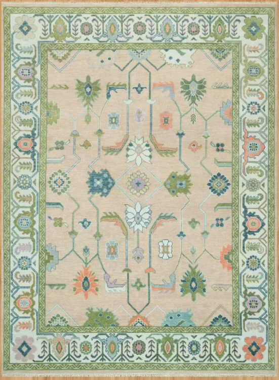 Hand-knotted wool oushak rug with a warm beige field, wide ivory-green border, and balanced medium-scale palmettes, rosettes, and tulips in green, teal, coral, and blue.
