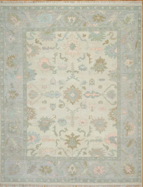 Hand-knotted wool oushak rug (8x10) with a very light ivory field, wide blue border, and open large-scale palmettes and rosettes in faint blue, olive, blush, and taupe.